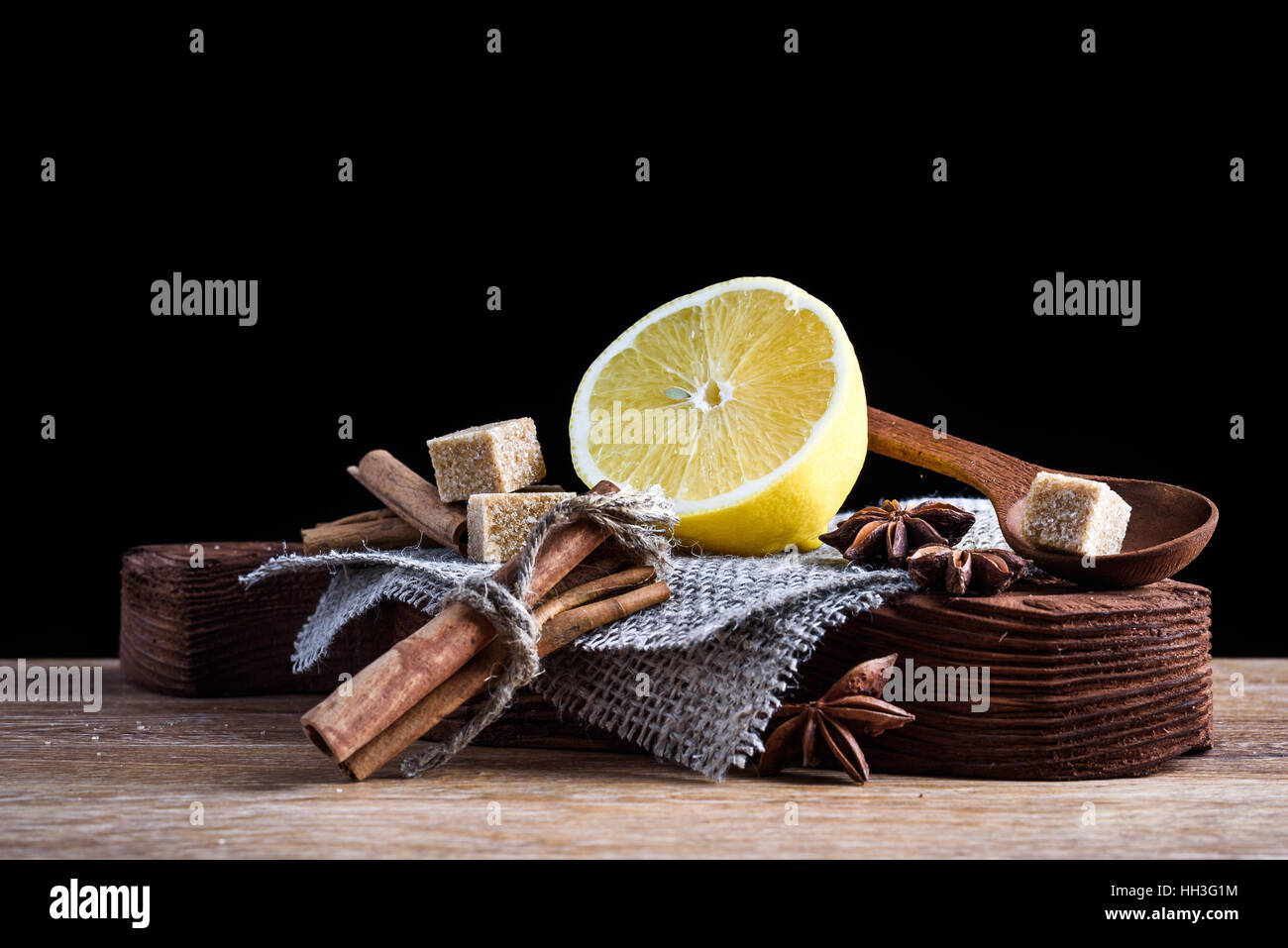set lemon, anise, cinnamon, brown sugar on old wooden Board isolated on dark background Stock Photo