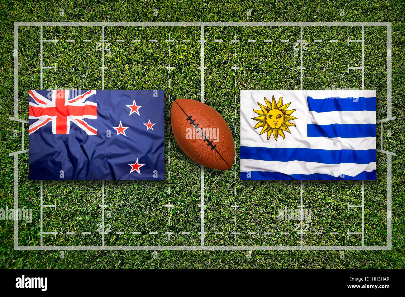 New Zealand vs. Uruguay flags on green rugby field Stock Photo