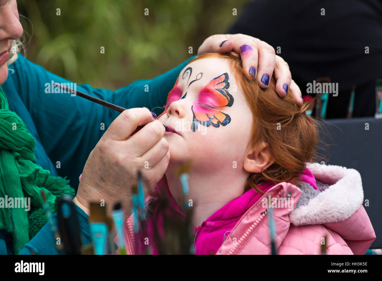 beautiful little girl with a painted fox on her face. face painting Stock  Photo