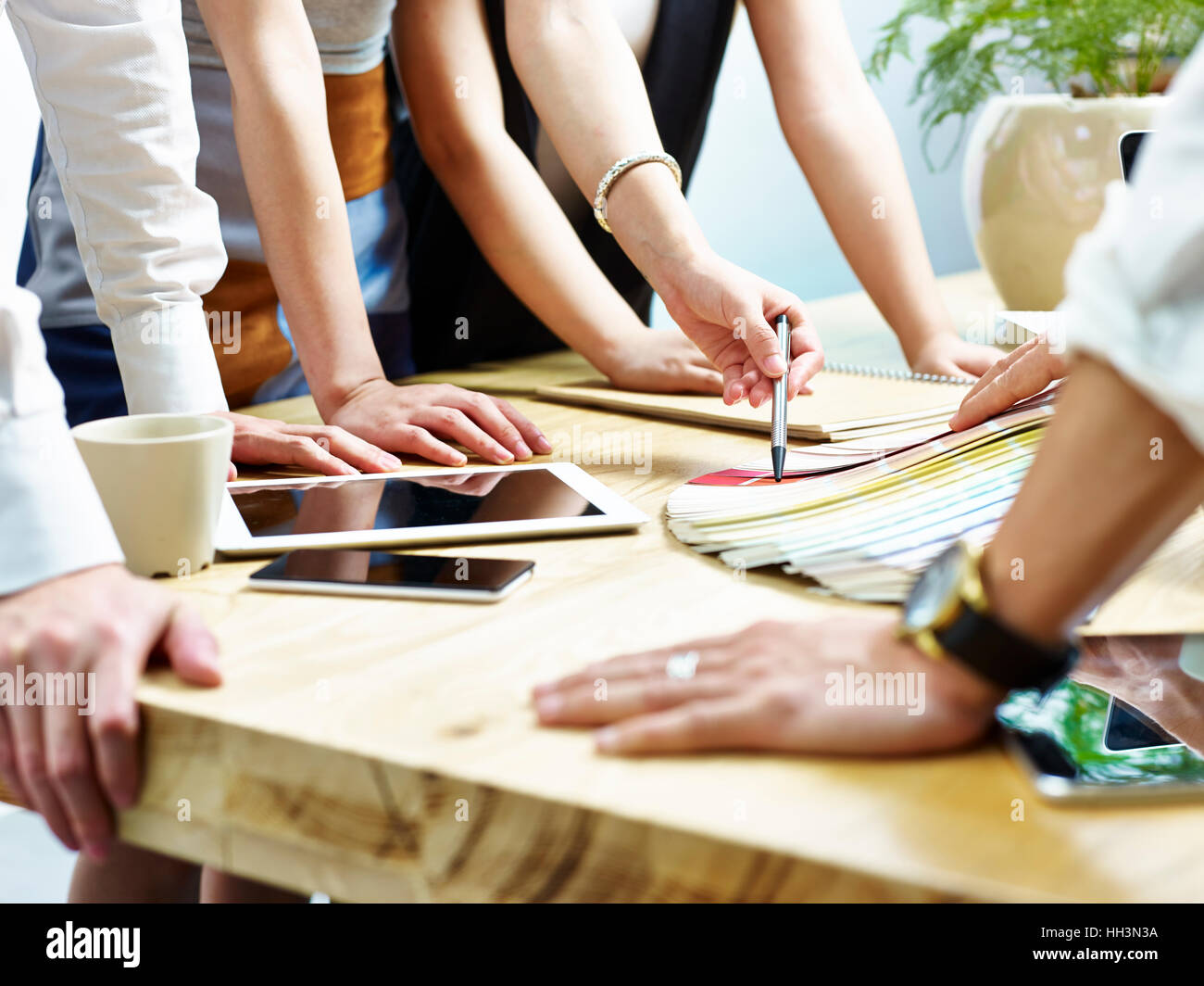 group of young designers working together deciding on a solution using color palette. Stock Photo