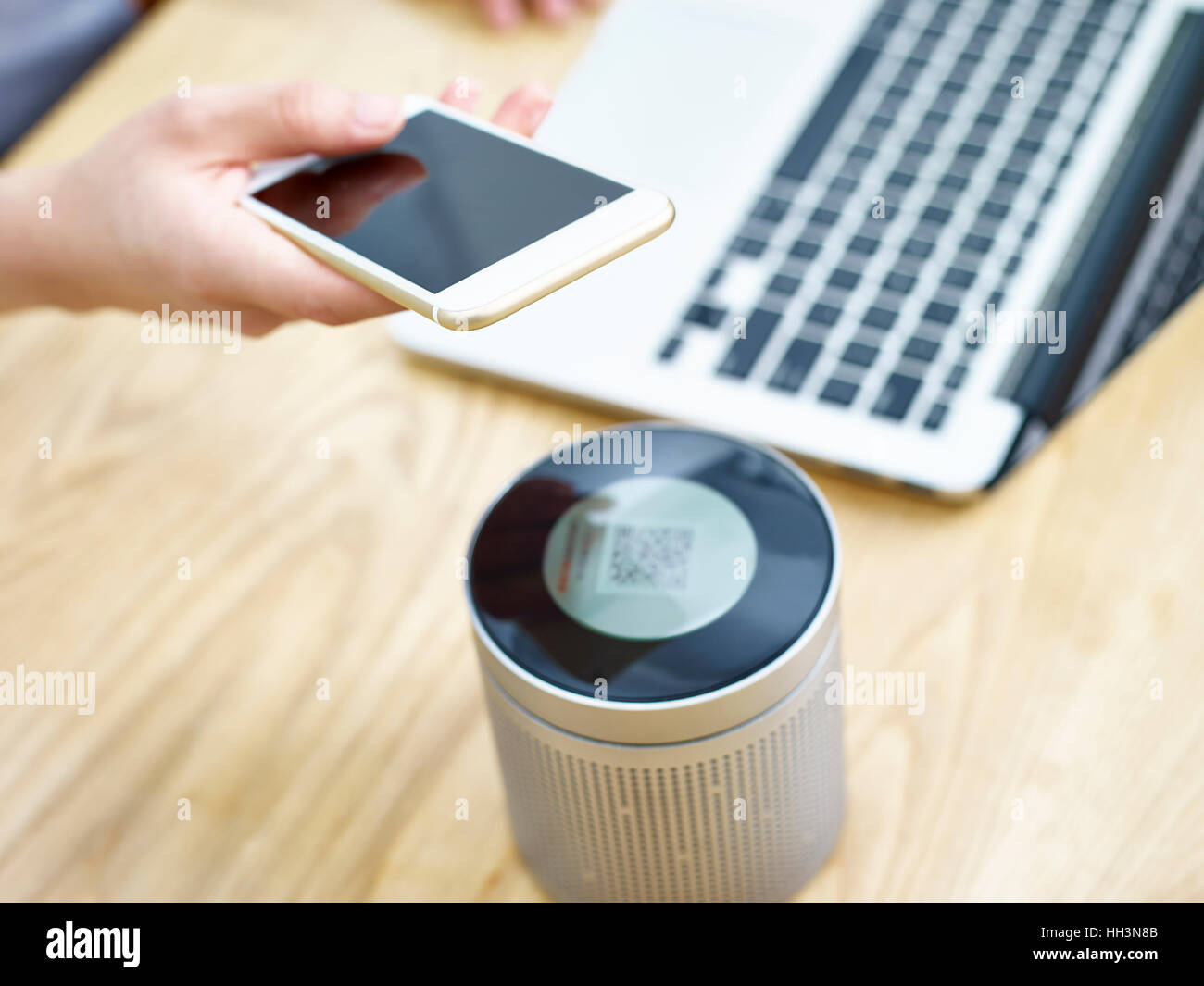 hand of a person holding cellphone playing music through a portable bluetooth speaker. Stock Photo