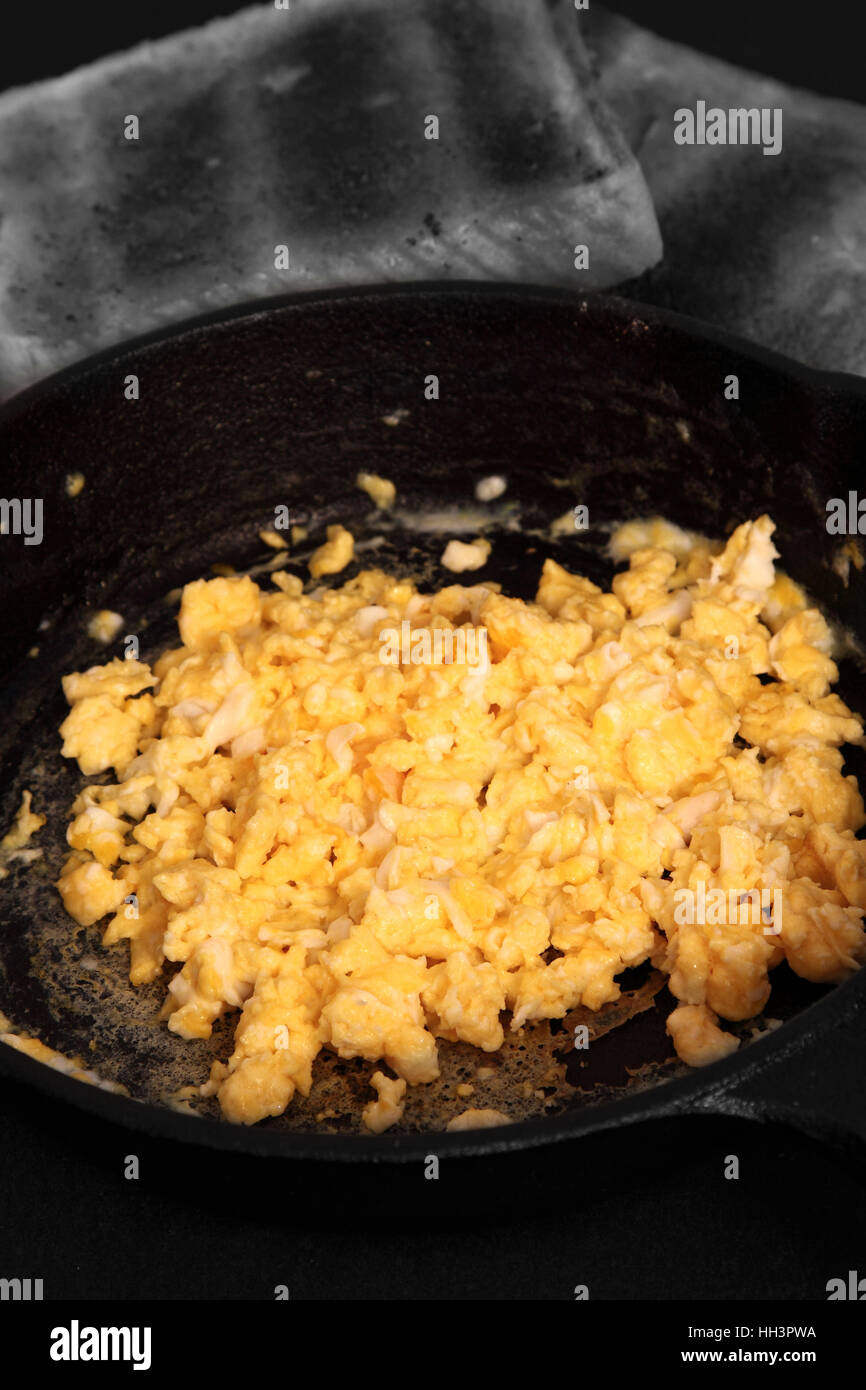 Scrambled egg in a cast iron frying pan with toast. Edited using