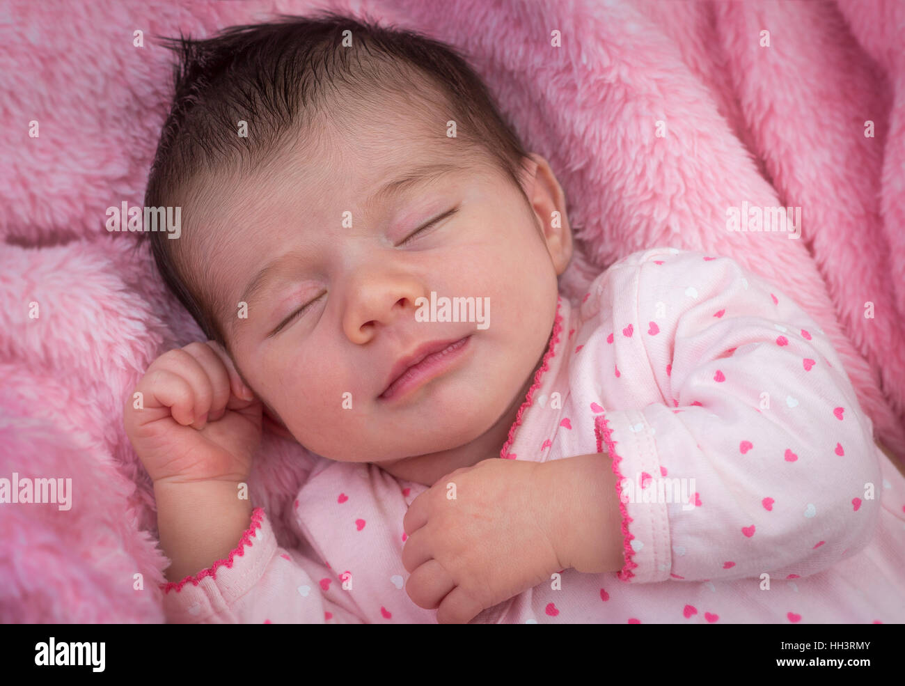 A less than three weeks of age cute baby, deeply sleeping on a pink blanket Nouveau-né à la couverture rose profondément endormi Stock Photo