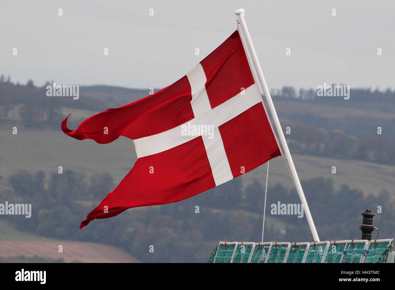 The Danish naval ensign flies proudly from the stern of KDM Peter Willemoes (F362), on passing Greenock's East India Harbour. Stock Photo