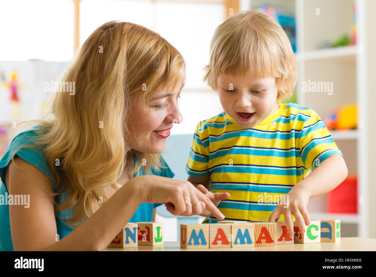 Mother teaches son child letters and words playing with cubes Stock Photo