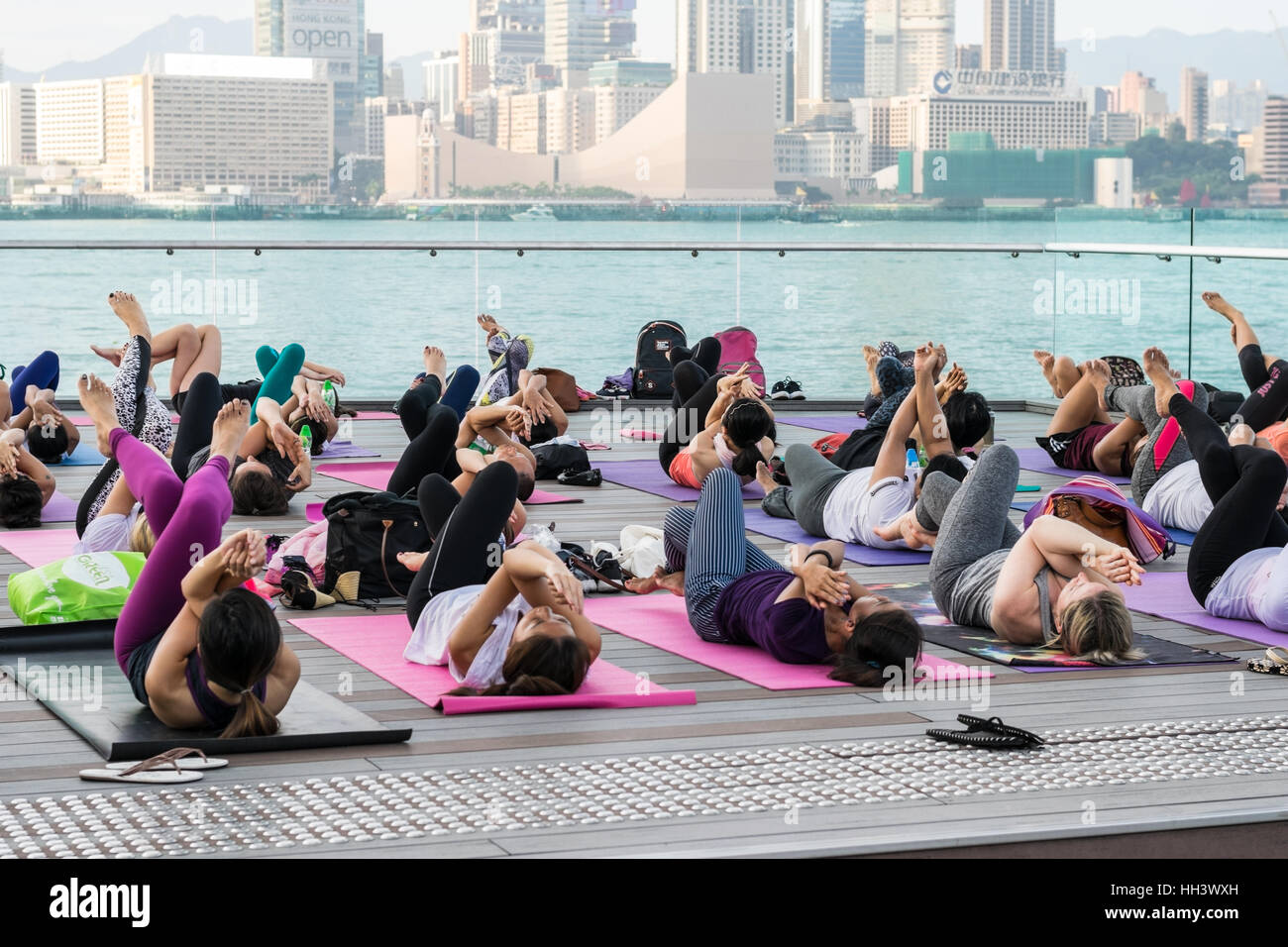 Group yoga outdoors with Victoria Harbor background, Hong Kong Stock