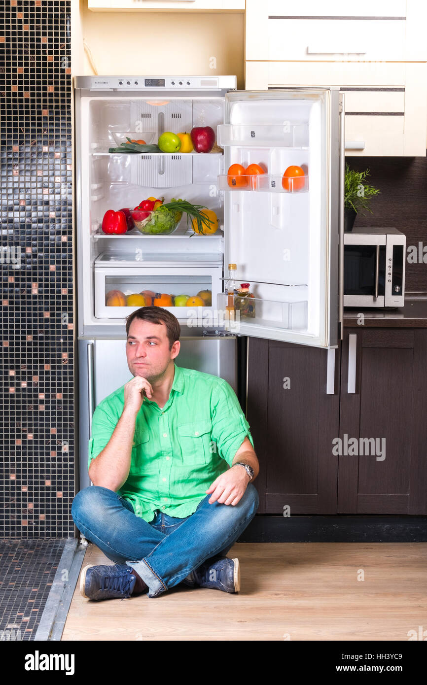 The man sitting next to open refrigerator Stock Photo