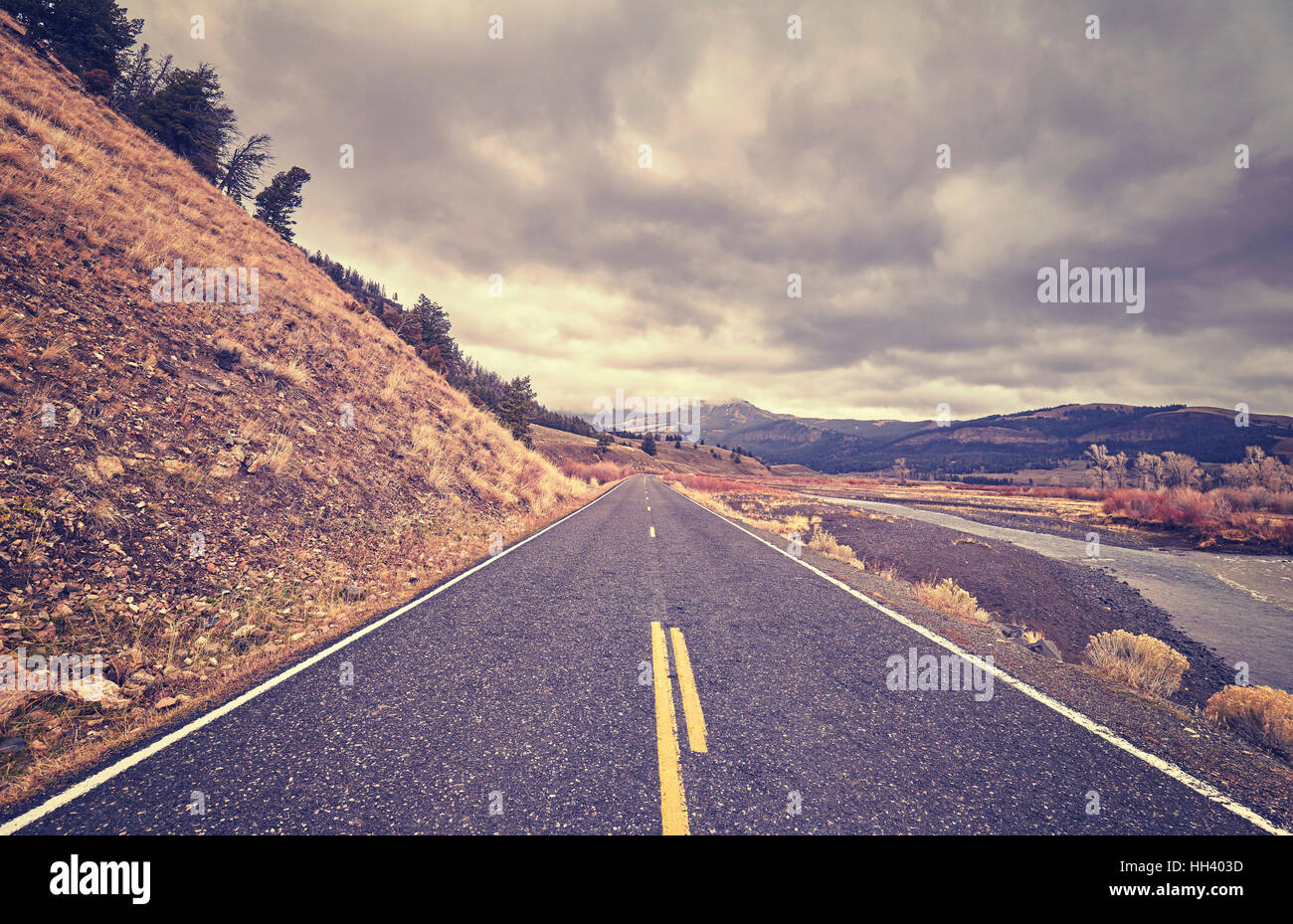 Vintage toned scenic road with stormy clouds, travel concept. Stock Photo