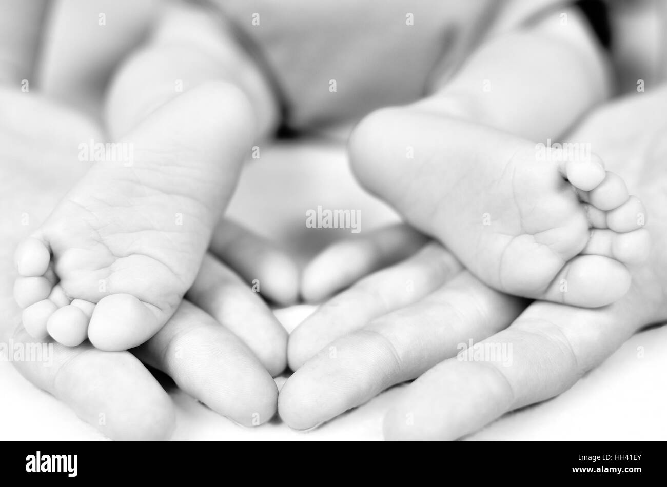 Mother hold baby leg in hand. Black and white image. Shallow focus Stock Photo