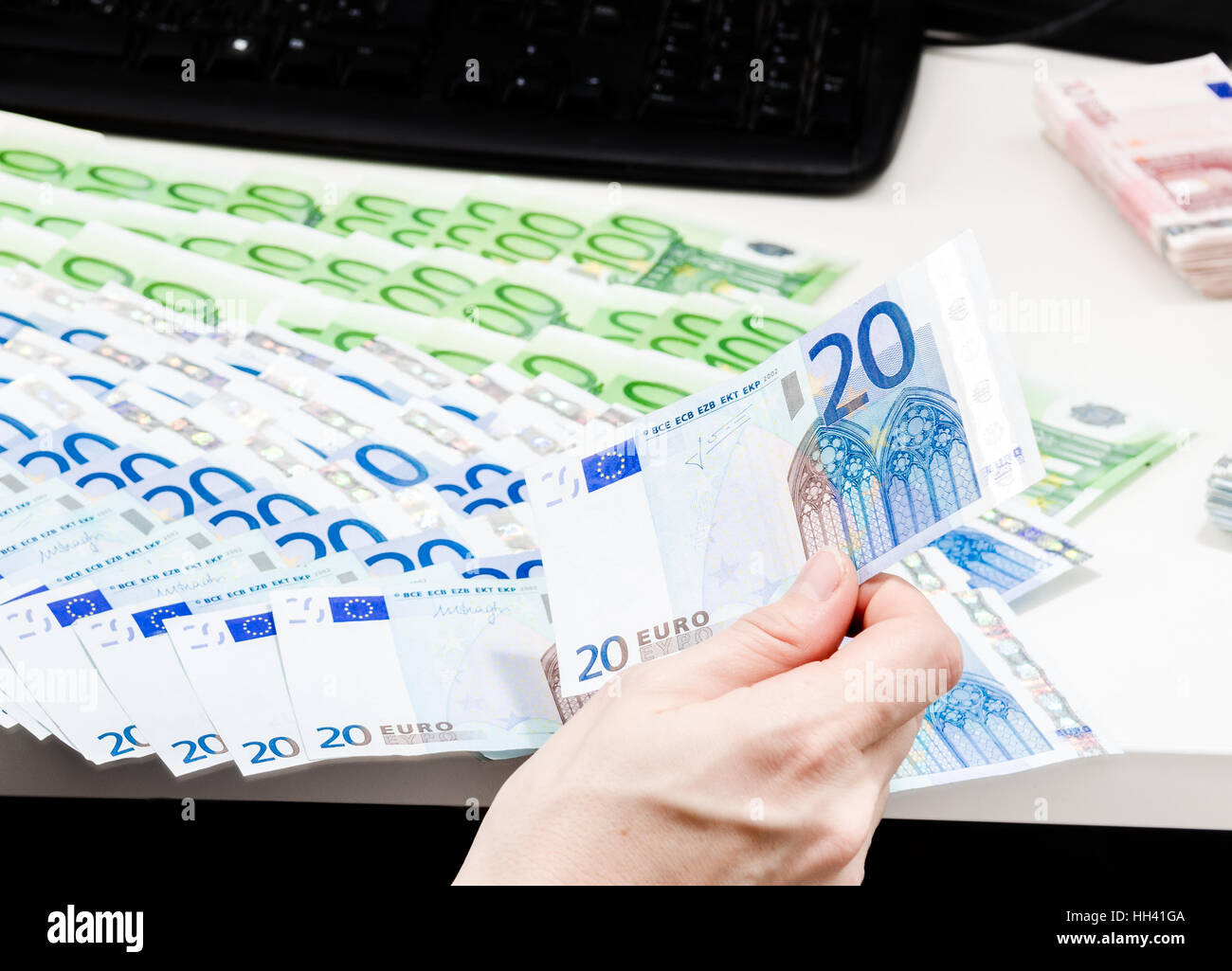 Bank Teller is counting money bills on a desk. Isolated on white. A woman is counting savings in euro currency on a white table. Stock Photo