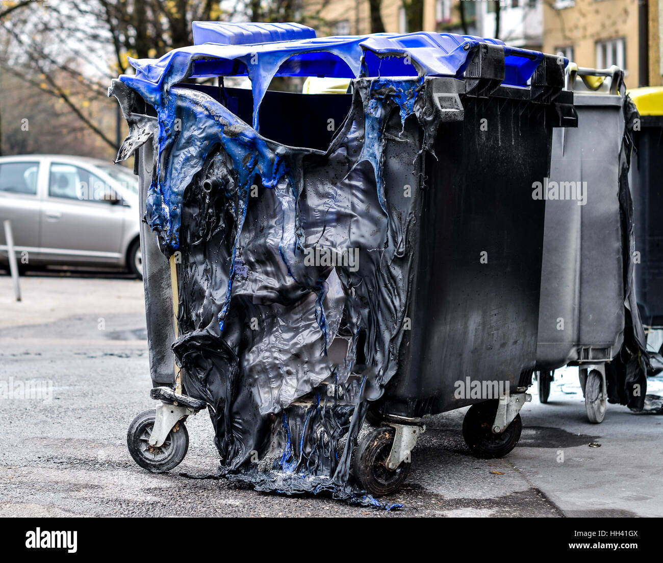Burnt and melted trash can from fire. Burned trash in waste container in the city is melted due to hot fire inside. Stock Photo