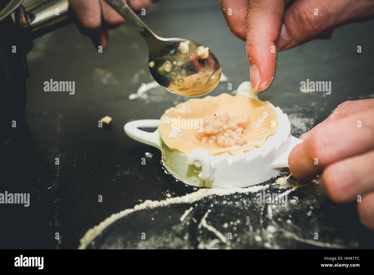 Making of homemade dumplings pastry tortellini. Model for home made pasta filled with meat. Woman's hand is preparing organic meal. Stock Photo