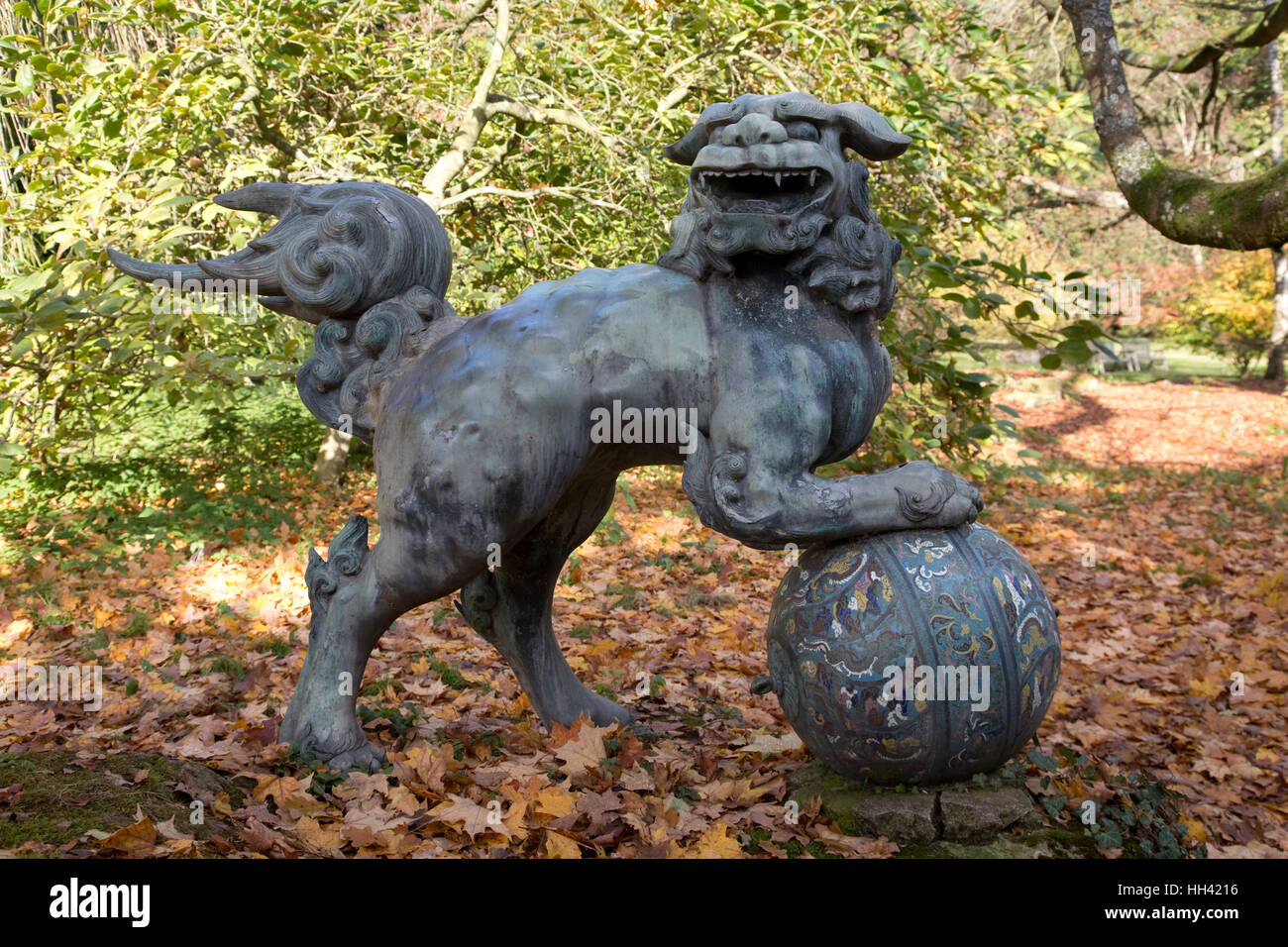 Bronze foo dog sculpture woodland Batsford Arboretum Cotswolds UK Stock Photo