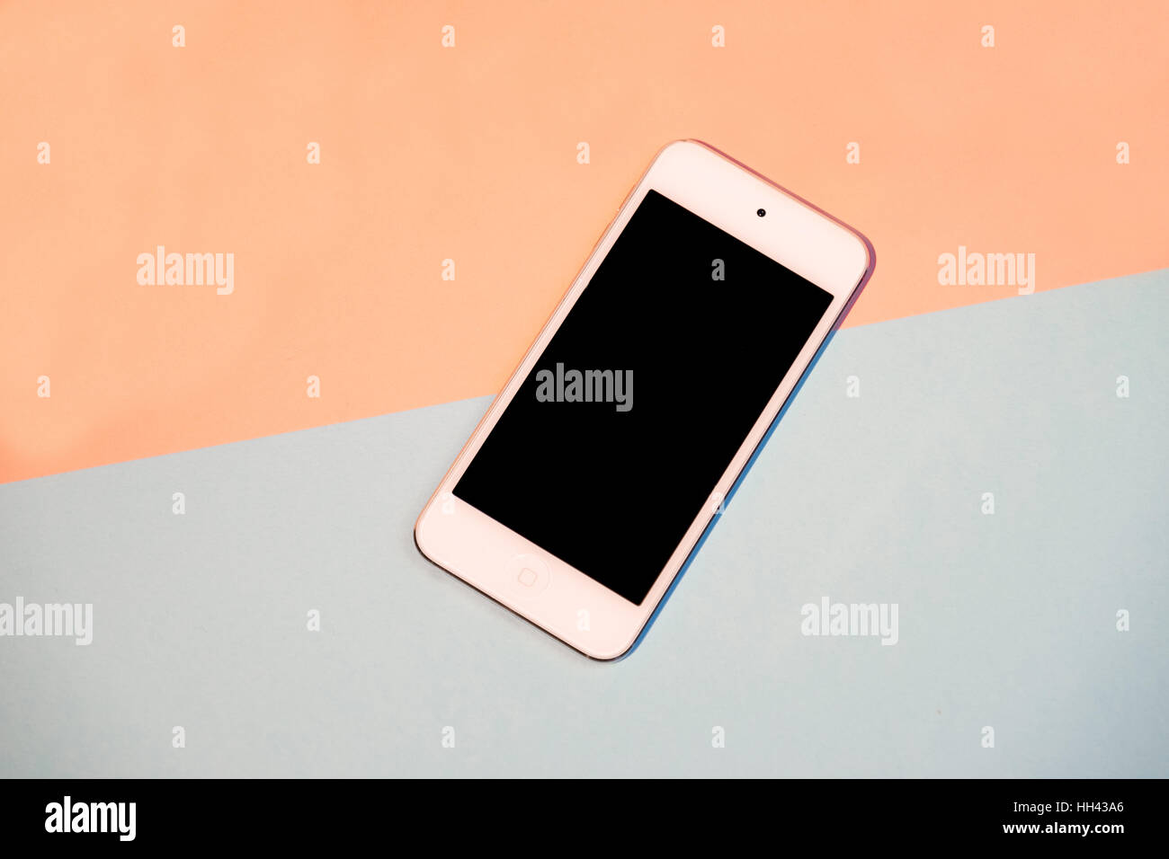 Smart phone against split pink and aqua background Stock Photo