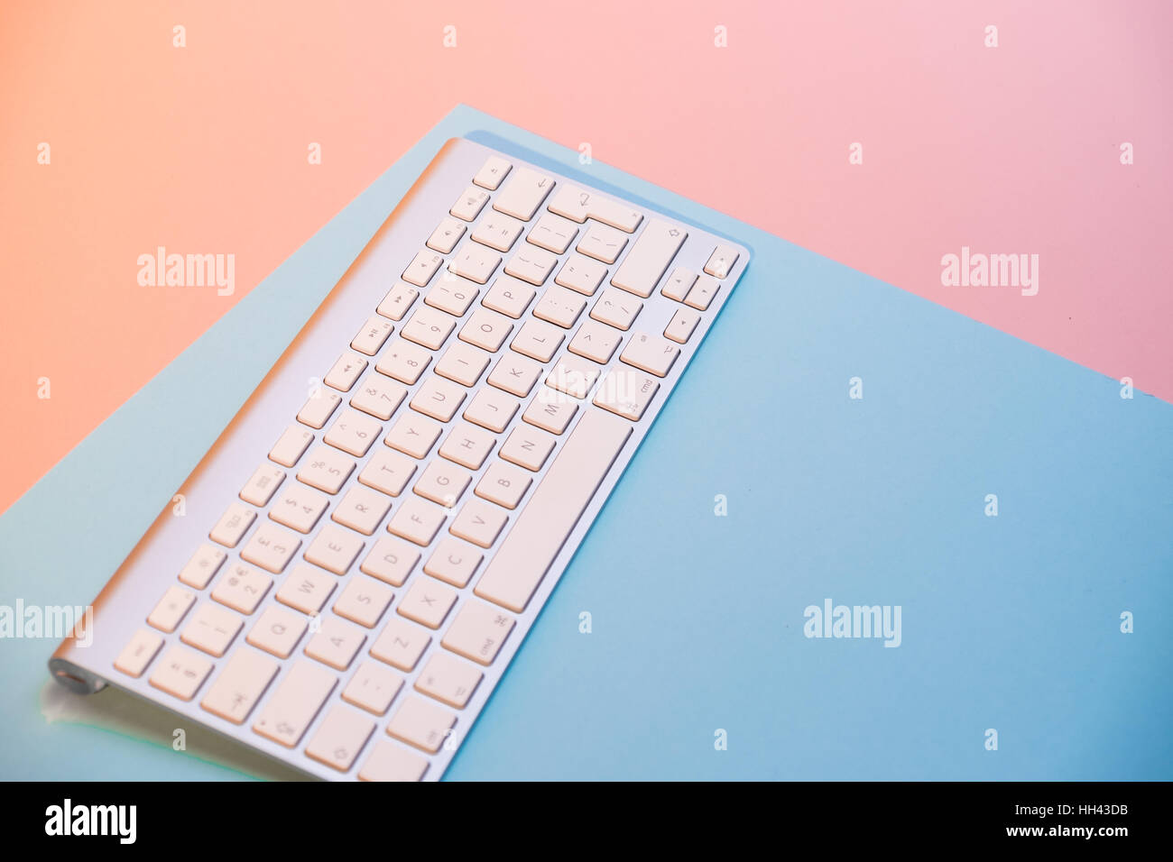 Wireless computer keyboard against pink and aqua backdrop Stock Photo