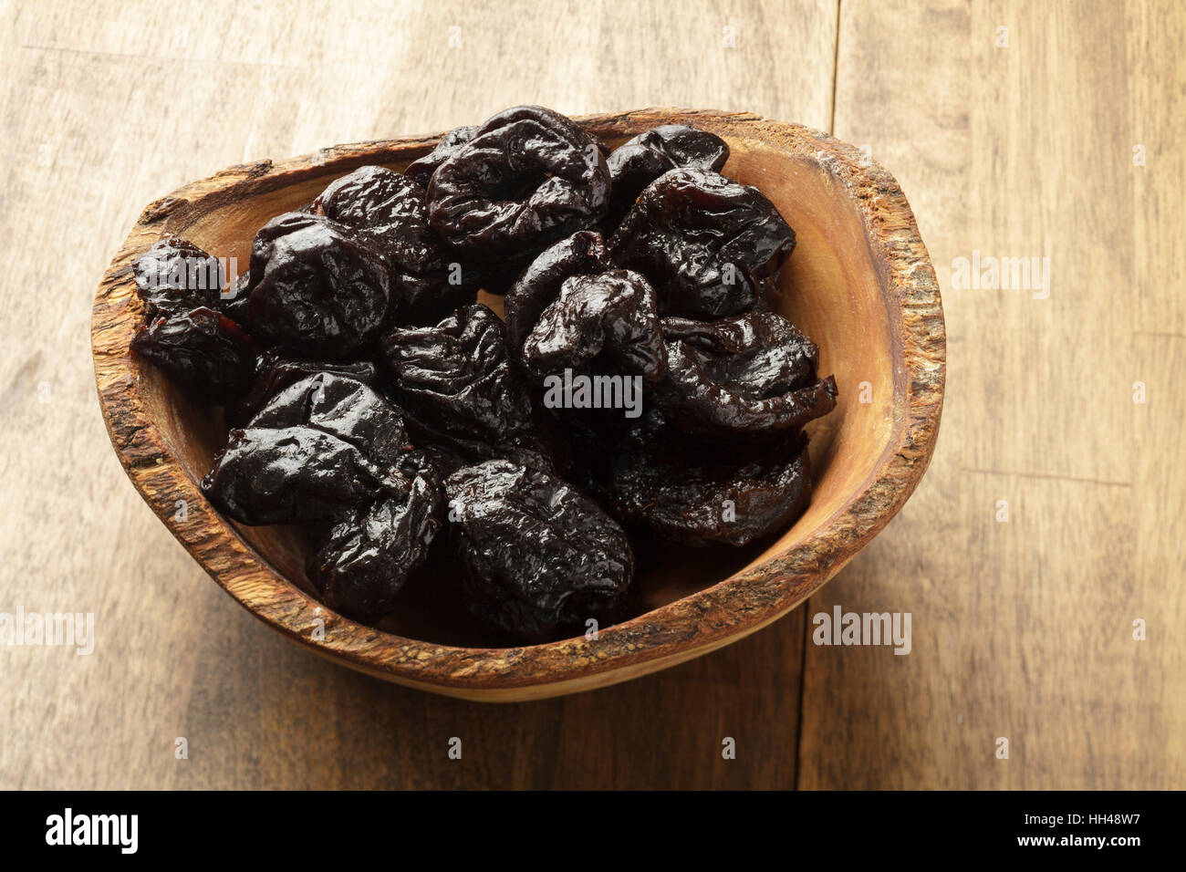 Prunes in wooden bowl Stock Photo