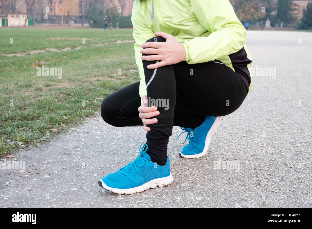 Runner with injured ankle while training in the city park in cold weather Stock Photo