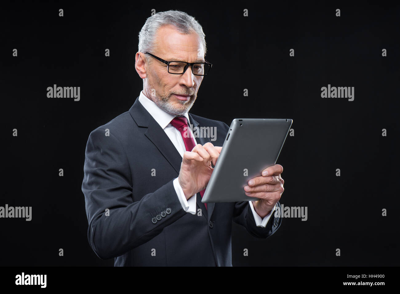 Mature businessman in eyeglasses using digital tablet Stock Photo