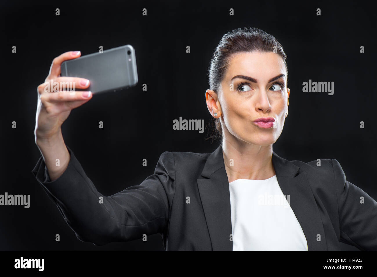 Businesswoman using smartphone and making duckface while taking selfie Stock Photo