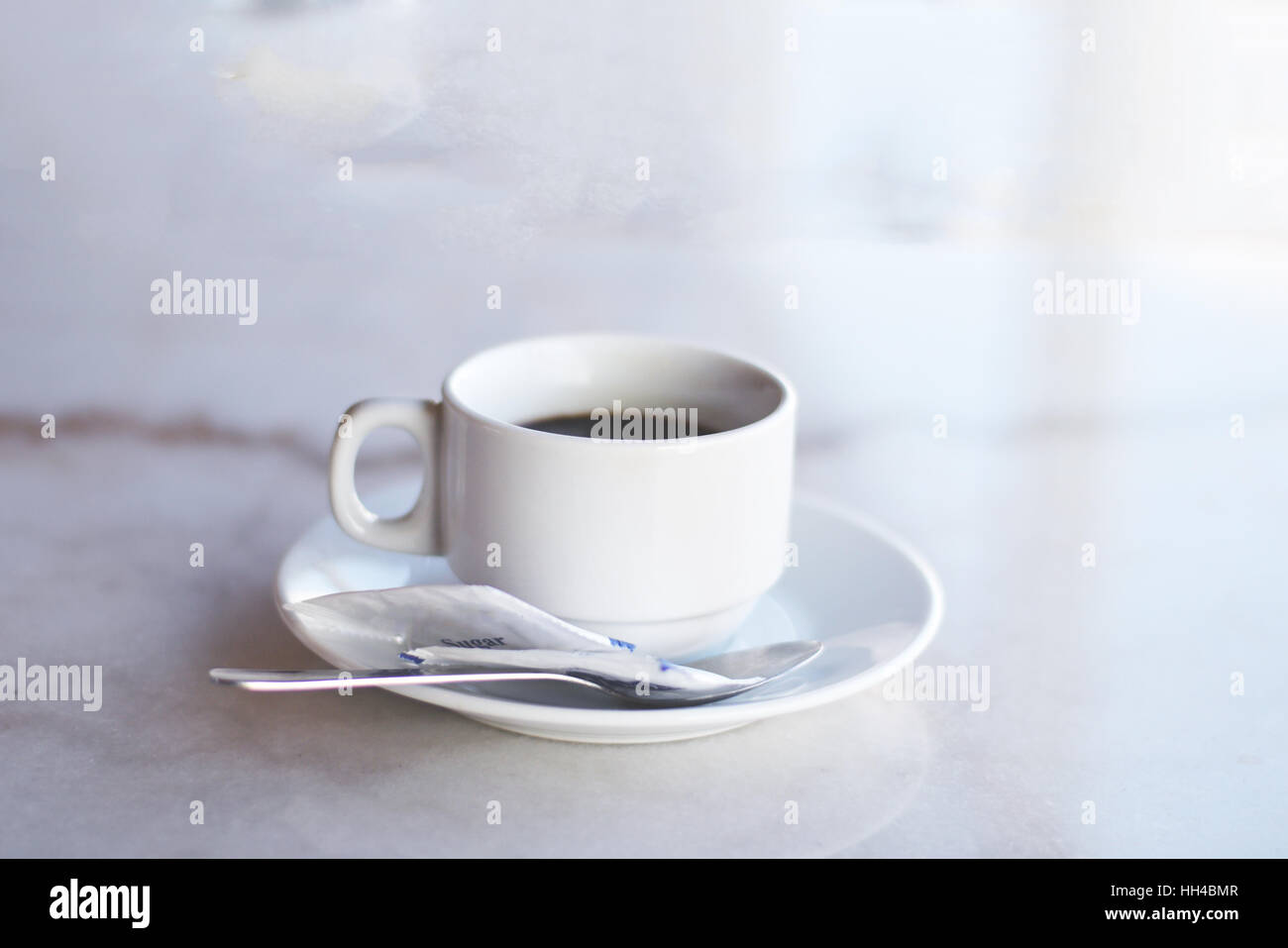 White Cup of coffee with tea spoon and sugar sachet on the saucer Stock