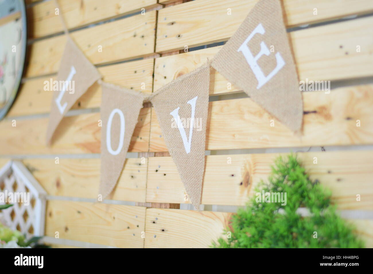 Hanging 'LOVE' letters besides wooden wall Stock Photo