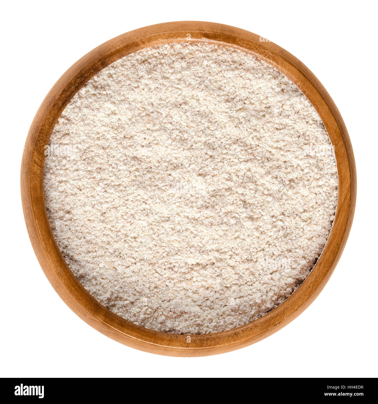 Whole-wheat flour in wooden bowl. Wholemeal flour, a powdery substance and basic food ingredient, made by grinding whole grain. Stock Photo