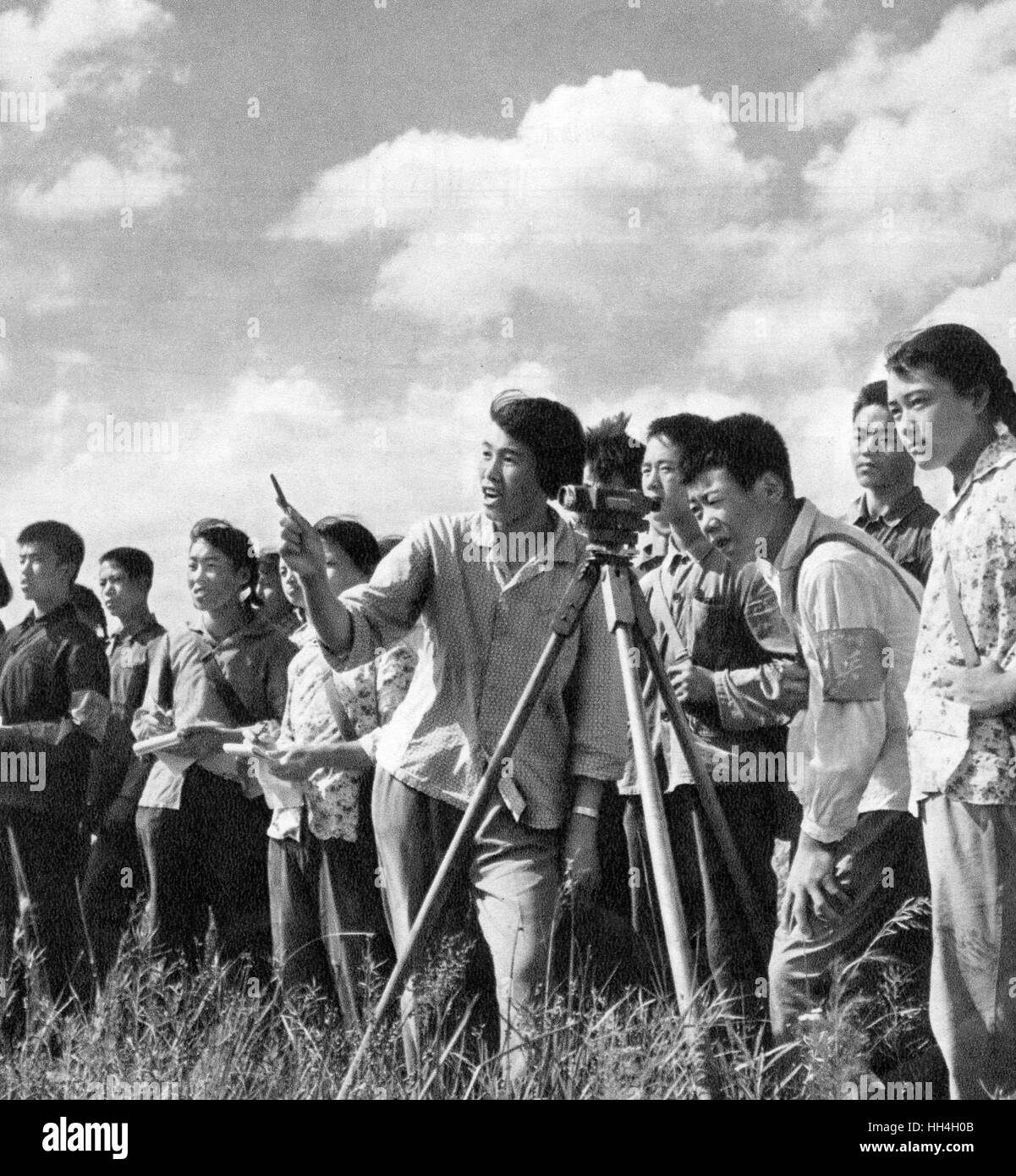 Communist China - young people with surveying equipment on a tripod in a field, doing a waterway survey and combining knowledge learnt in school with practical activities. Stock Photo