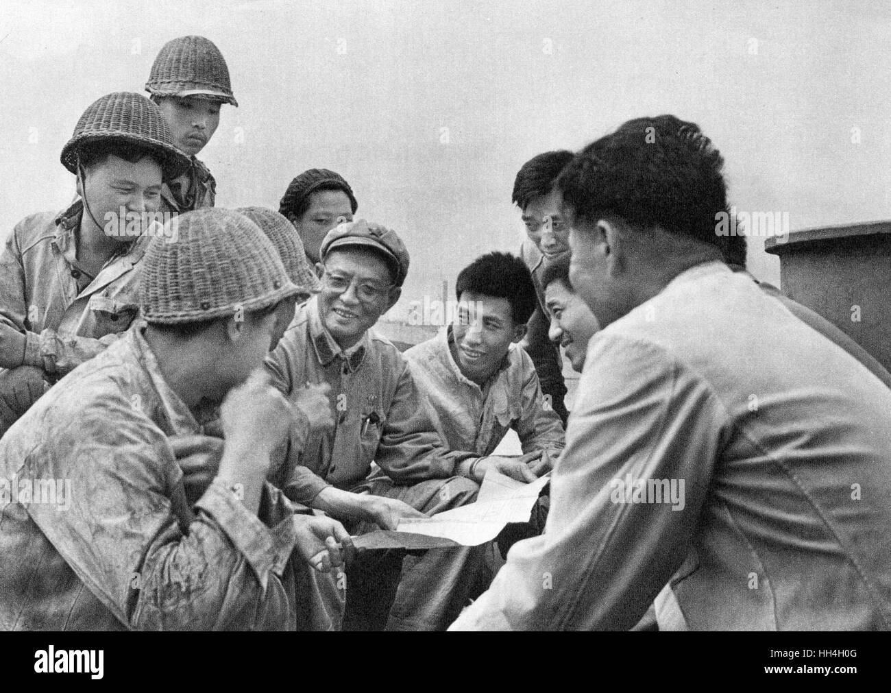 Communist China - shipbuilding yard workers and technicians with plan, working together to raise standards during the Cultural Revolution era. Stock Photo