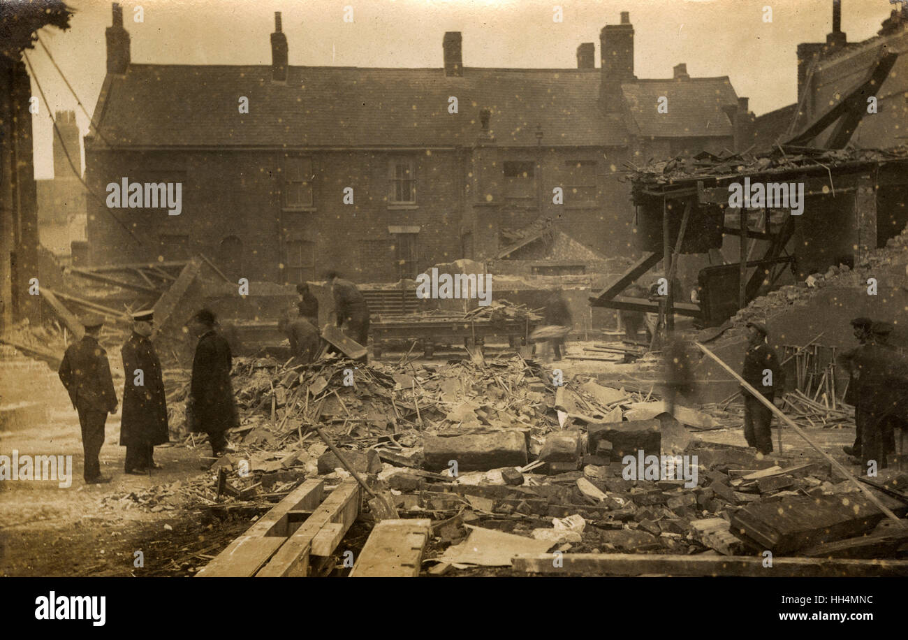 Assessing the damage after a bombing raid during the First World War, possibly in London. People sort through rubble, with a snooker table in the middle distance. Stock Photo