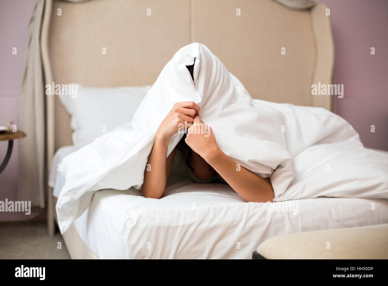 Woman hiding under a blanket. Stock Photo