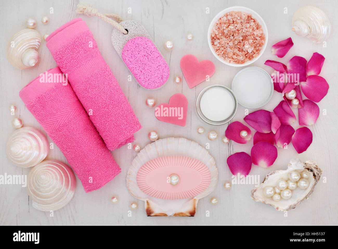 Bathroom and spa accessories with rose petals, himalayan salt, pumice,  soaps, pink face towels, shells and pearls on distressed wood background  Stock Photo - Alamy, image size:1300x956