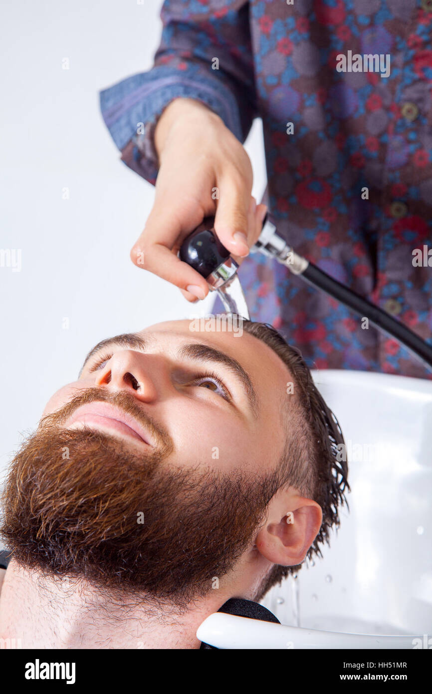 Hairstyling. Cropped image of barber washing head of his client in barber shop while preparing to haircut Stock Photo