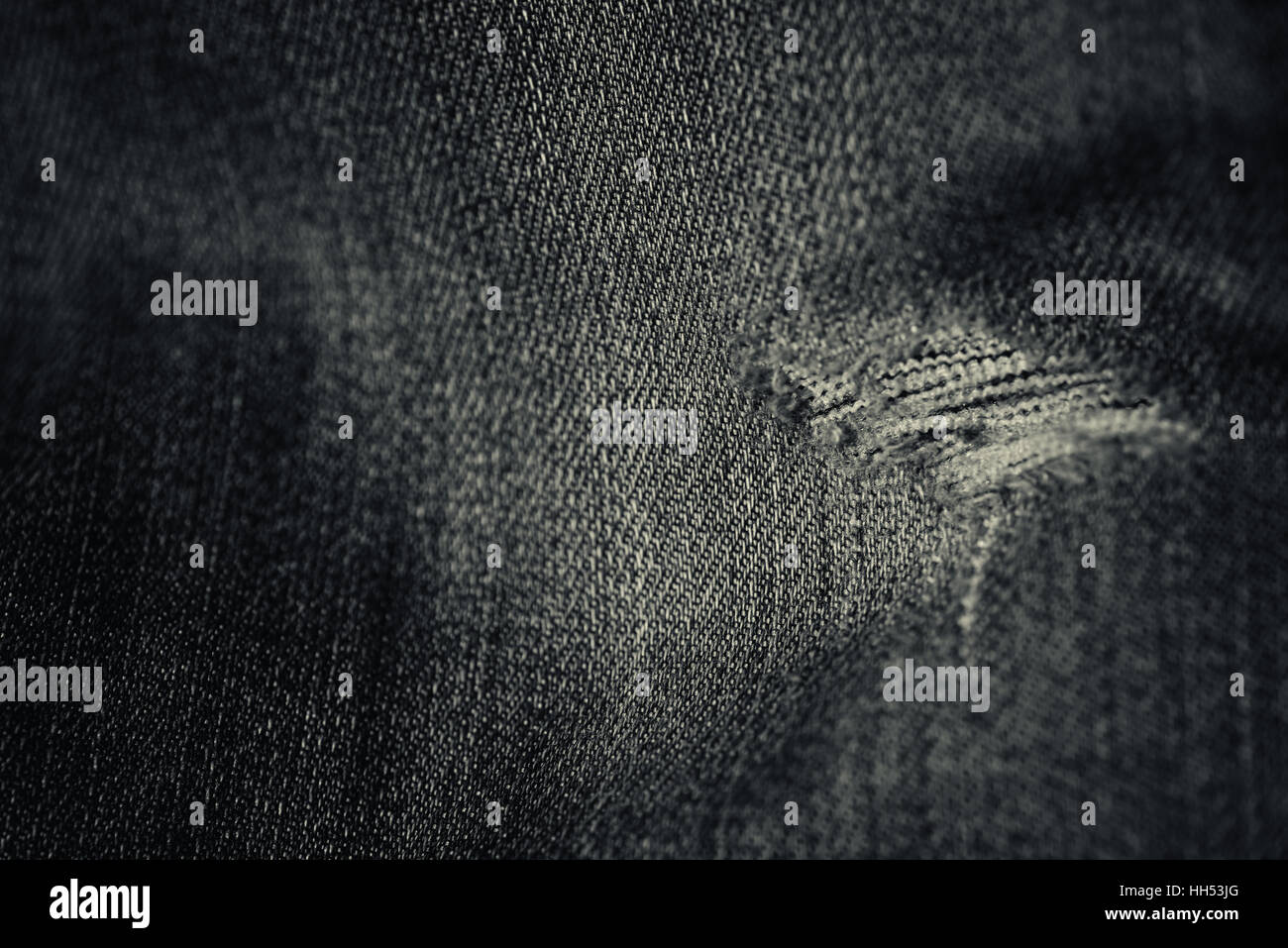 Word and faded denim jean material with a frayed hole in a horizontal composition in black and white with worn material. Stock Photo