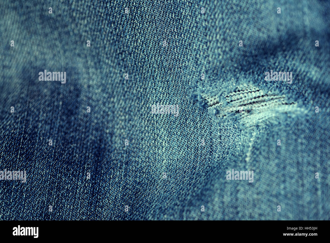 Word and faded denim jean material with a frayed hole in a horizontal composition in color. Stock Photo