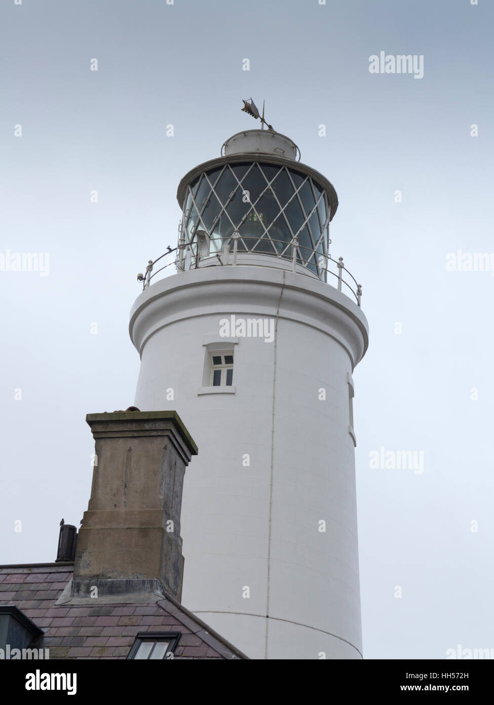 The top section of Southwold lighthouse with a chimney in front on a dull misty day Stock Photo