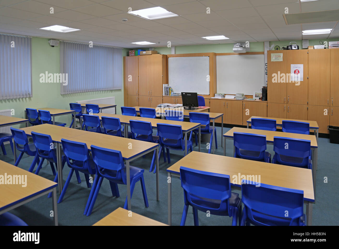 Wide-angle view of a newly built school classroom showing desks and chairs in a traditional layout, facing the teachers desk Stock Photo
