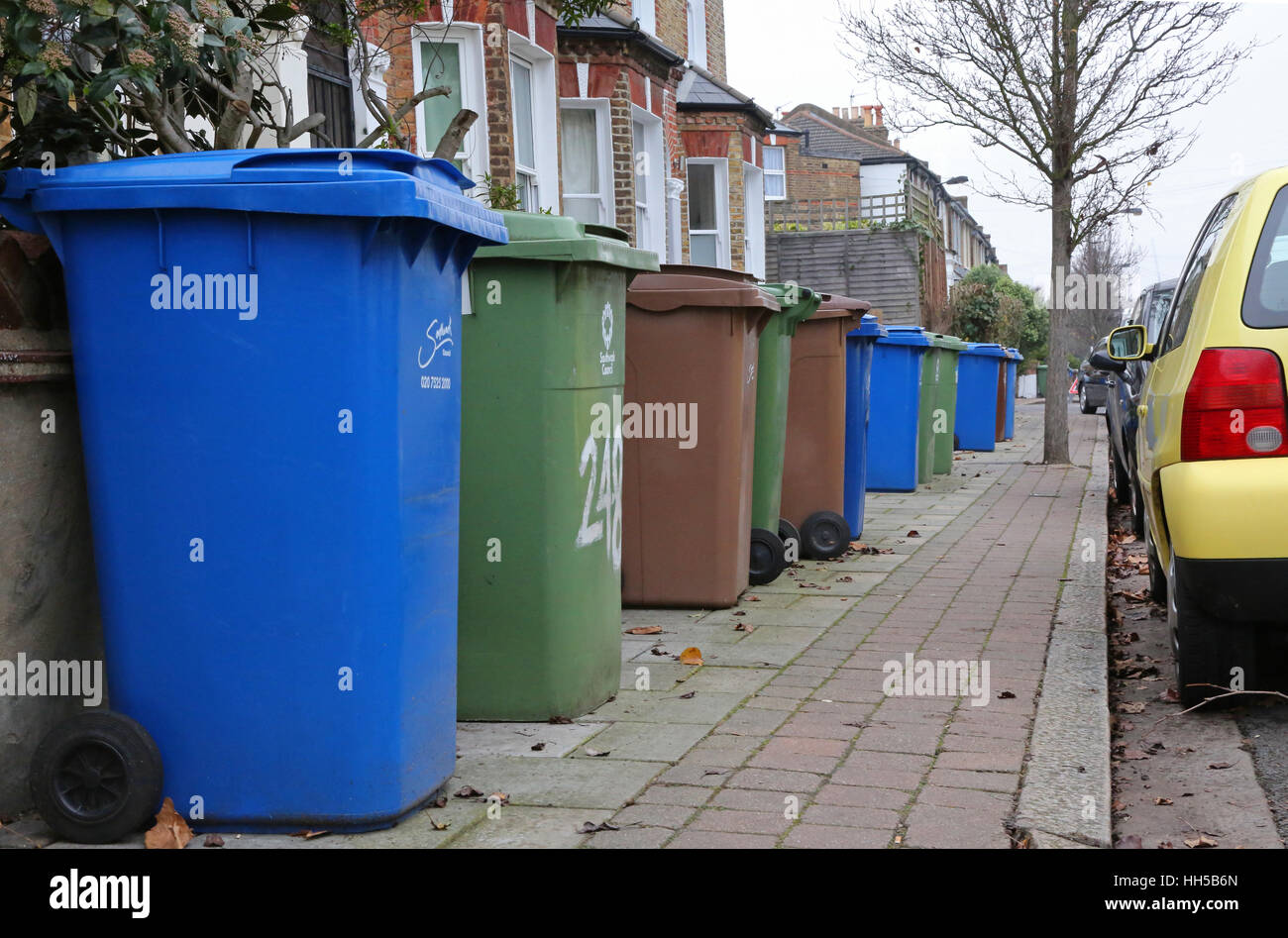 Plastic 'wheelie bins' crowd the pavement in a south London residential street, Peckham. UK Stock Photo
