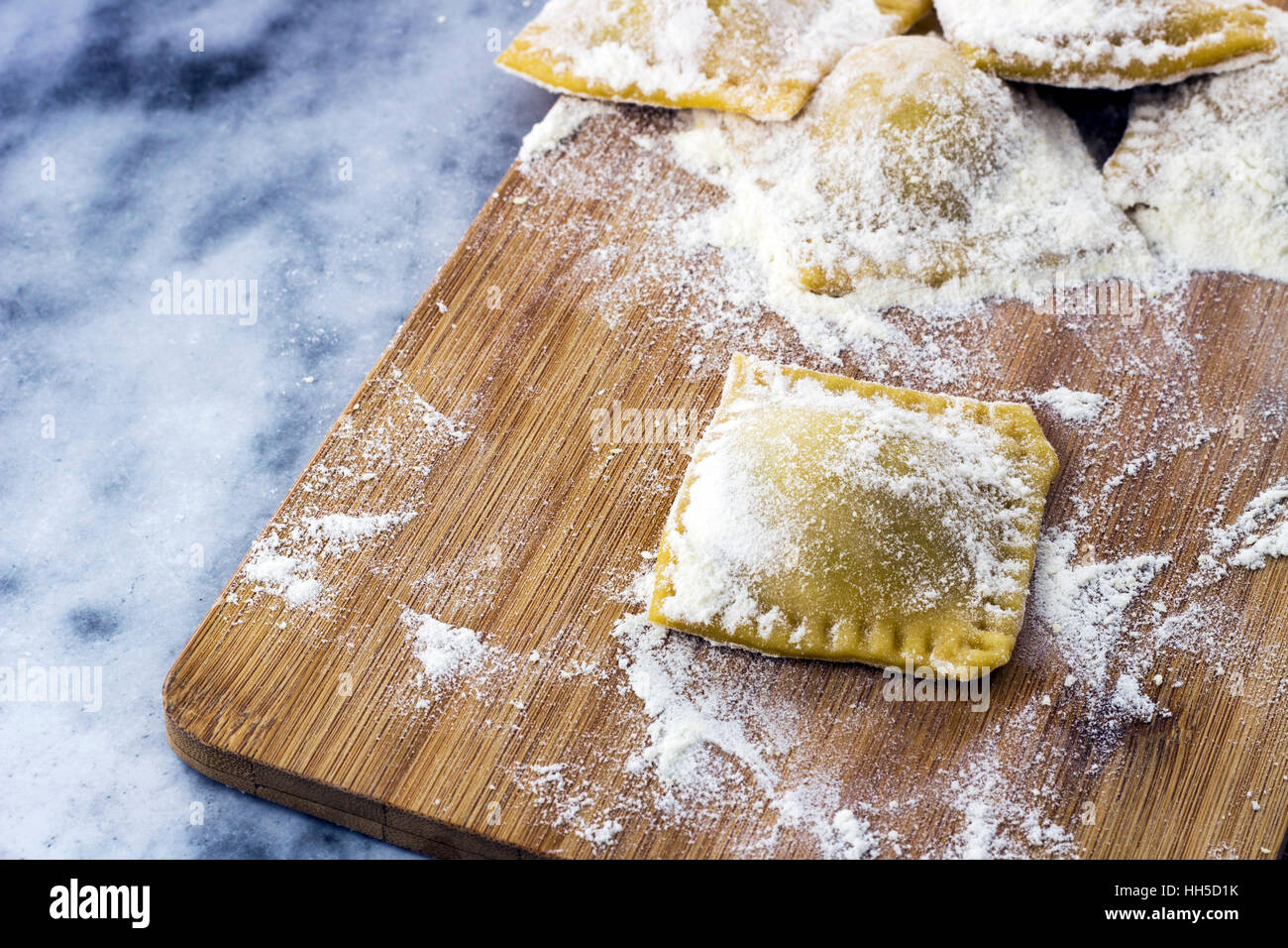 Floured Italian ravioli with black pepper on a marble background Stock Photo