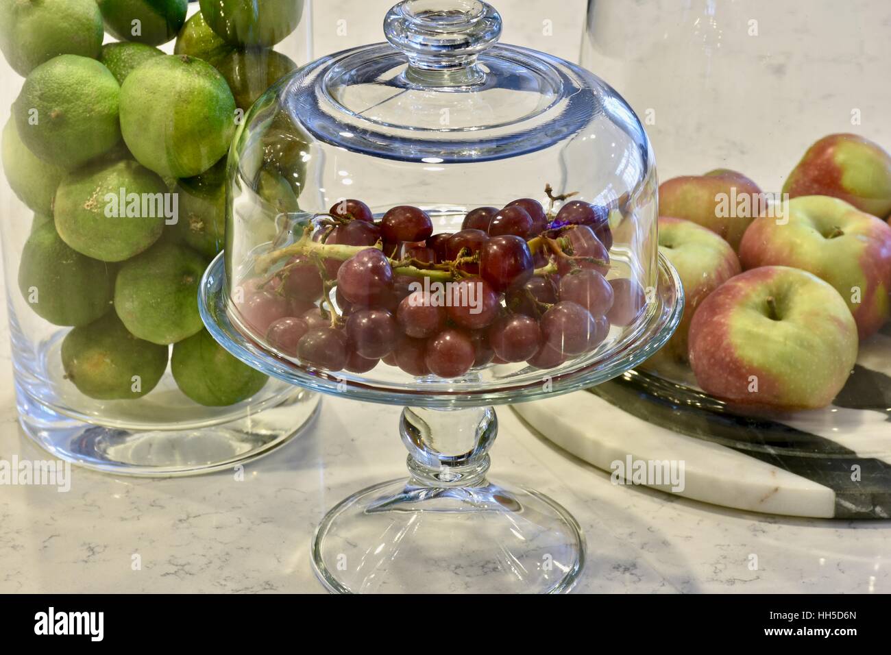Fresh fruit in glass containers on a white marble surface in a modern