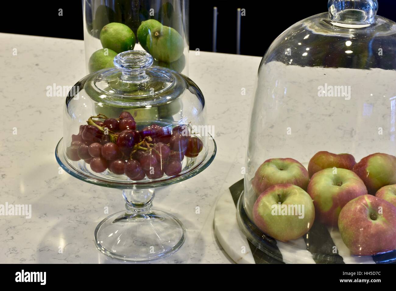 Fresh fruit in glass containers on a white marble surface in a modern