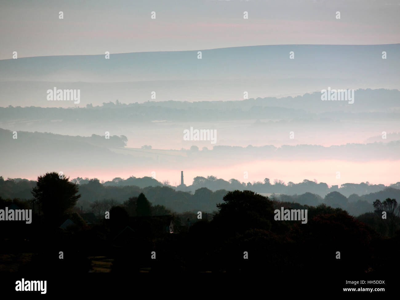 Bands of early morning mist produce a layered landscape with trees and ...