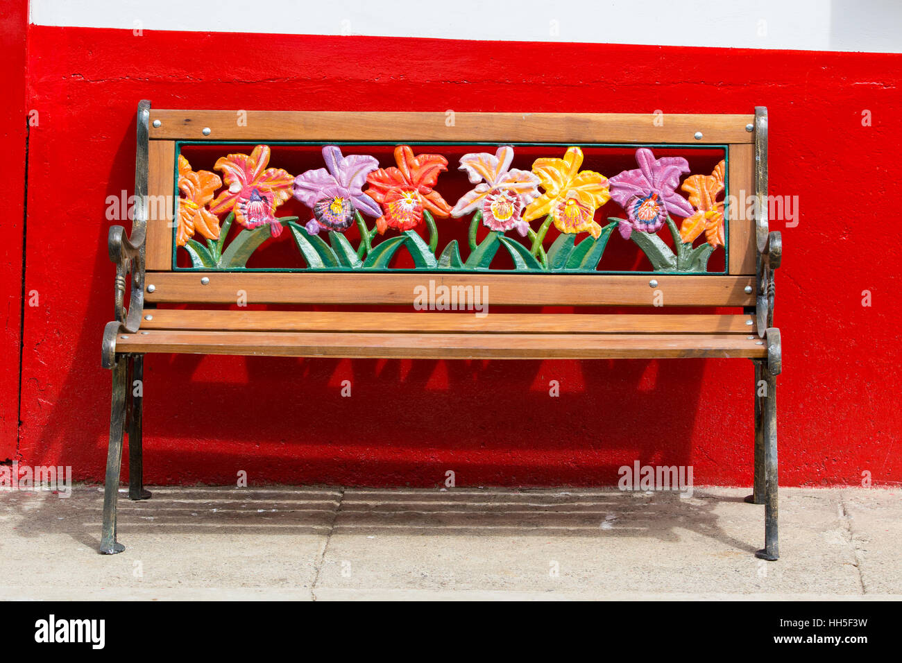 Colorful bench with floral motives against a red wall, El Jardin Colombia Stock Photo
