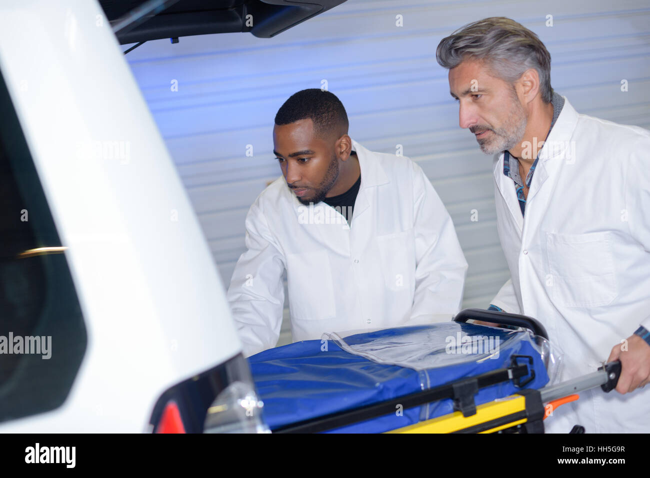 Loading Ambulance Ambulance men loading stretcher into vehicle Stock Photo - Alamy
