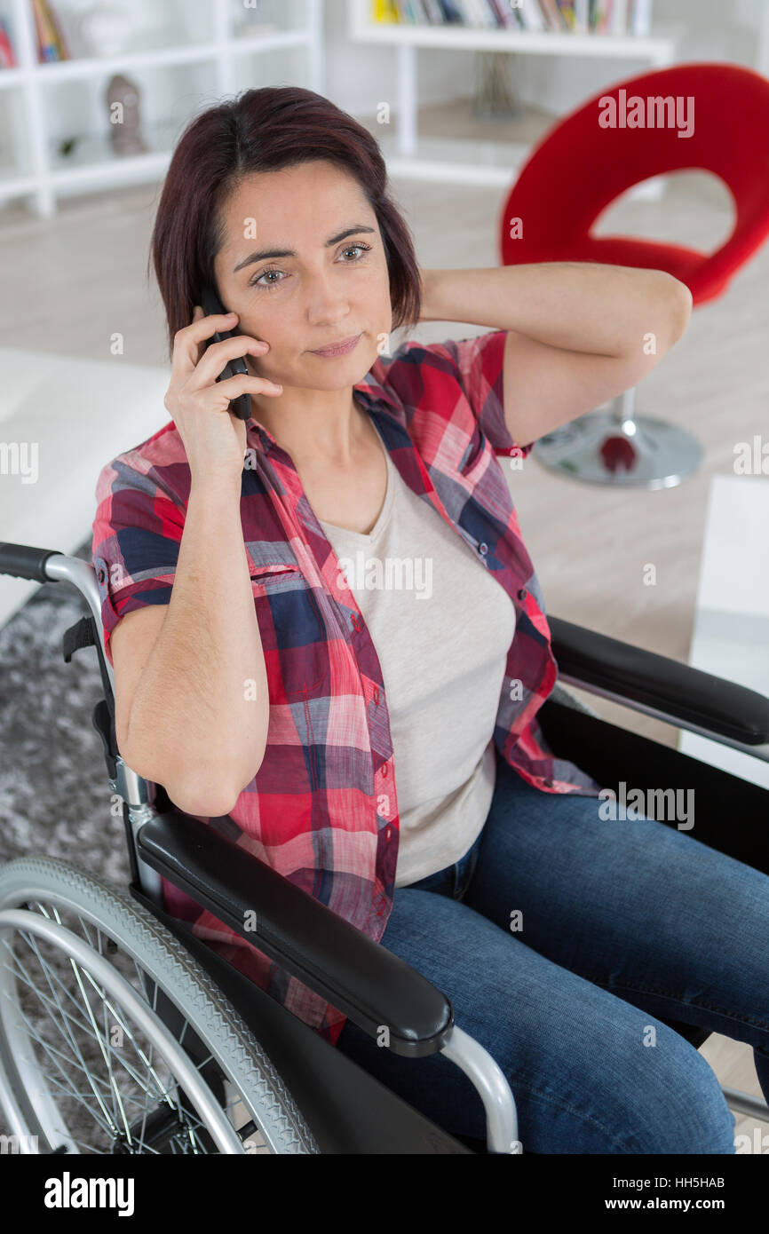 disabled woman in wheelchair making call on mobile phone Stock Photo