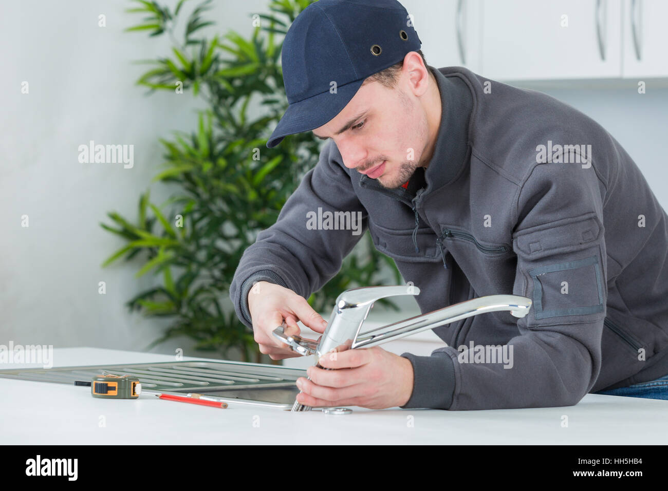 Plumber fitting tap to kitchen sink Stock Photo Alamy