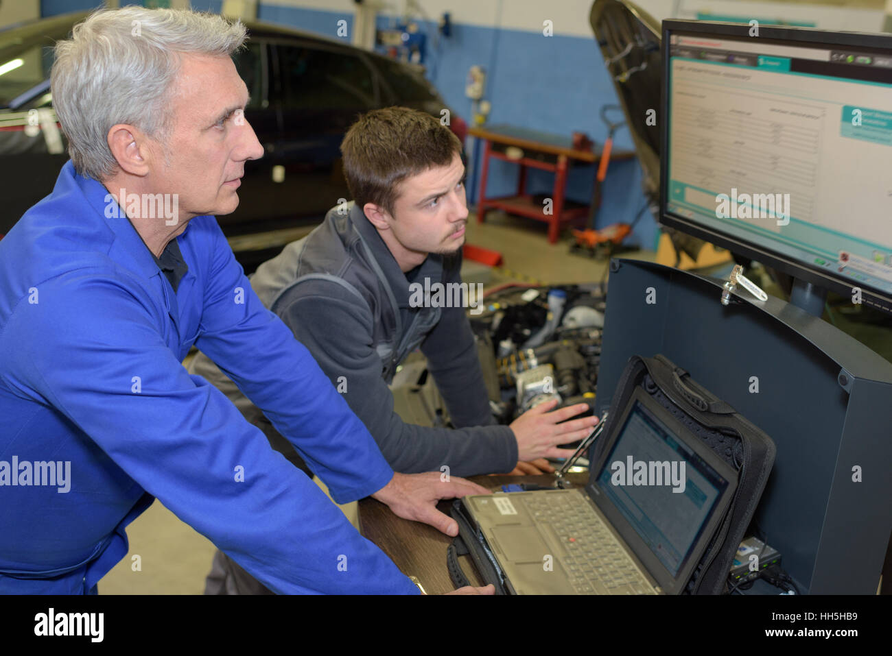 auto mechanic teacher and trainee performing tests at mechanic school