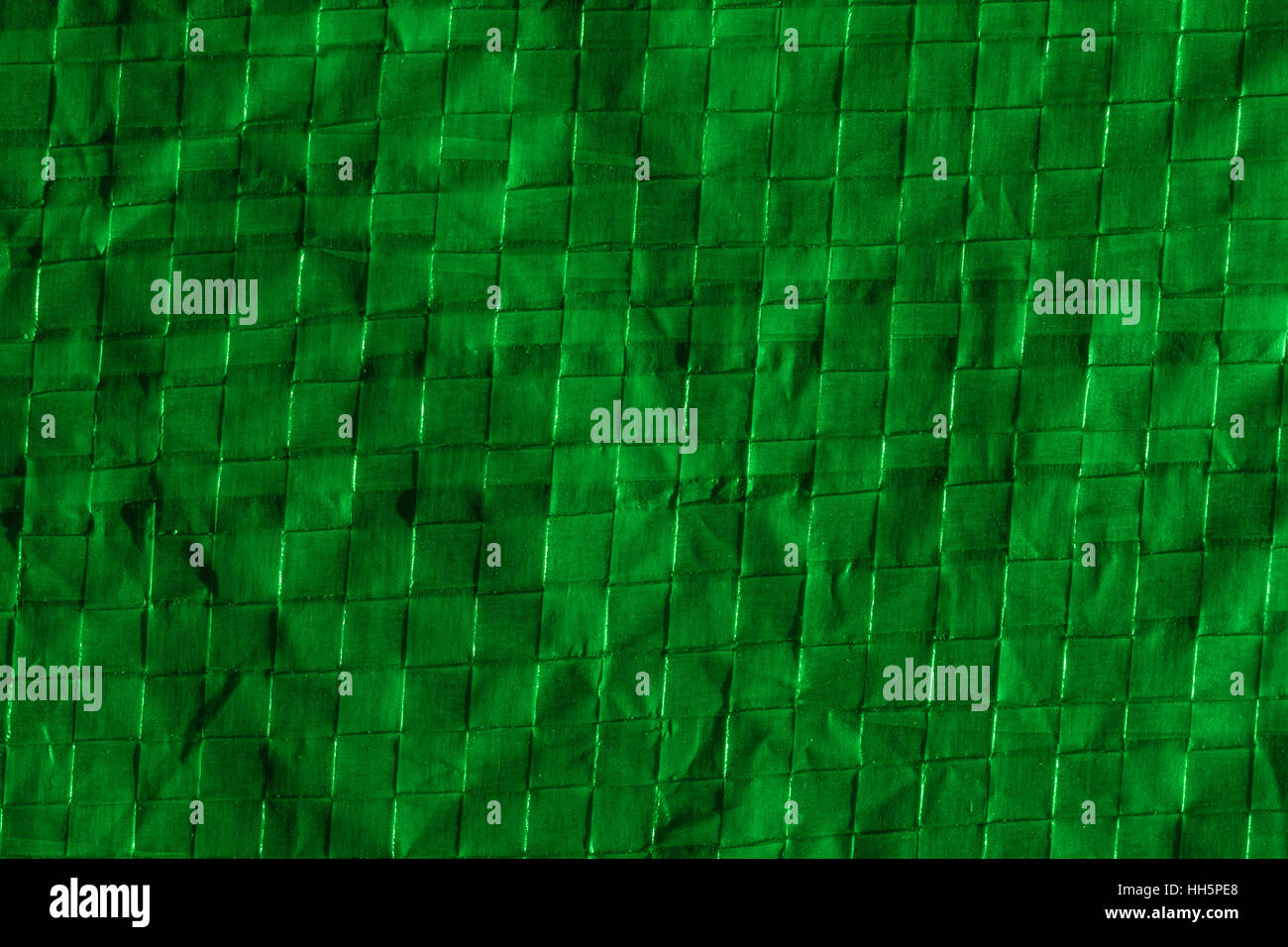 Abstract macro photo of section of green lit polymer ground sheet / tarpaulin used for camping. Almost looks like bamboo. Protective layer metaphor. Stock Photo