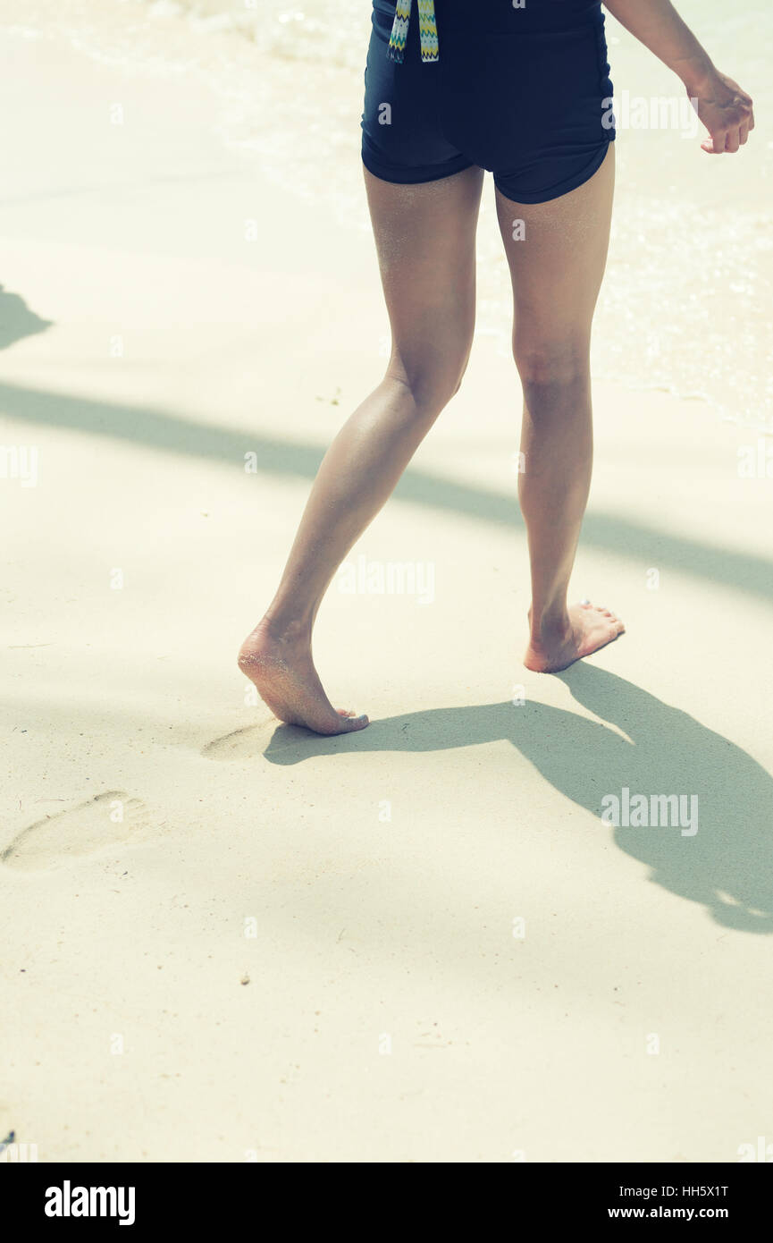 woman walking on sand beach leaving footprints in the sand Stock Photo ...