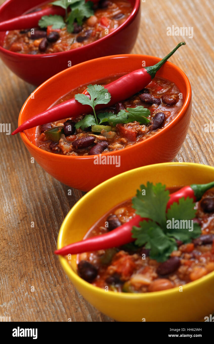 Photo of three bowls of chili resting on an old wood table. Stock Photo