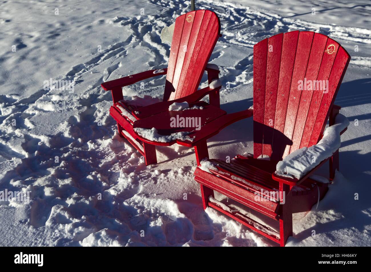 Red Adirondack Chairs or Adirondacks and Snow Tracks. Sunny Winter Day